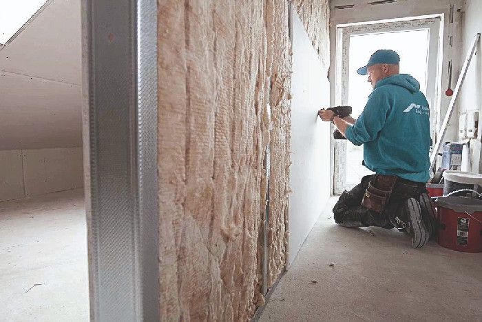 Ein Handwerker beim Wand einziehen im Dachgeschoss.
